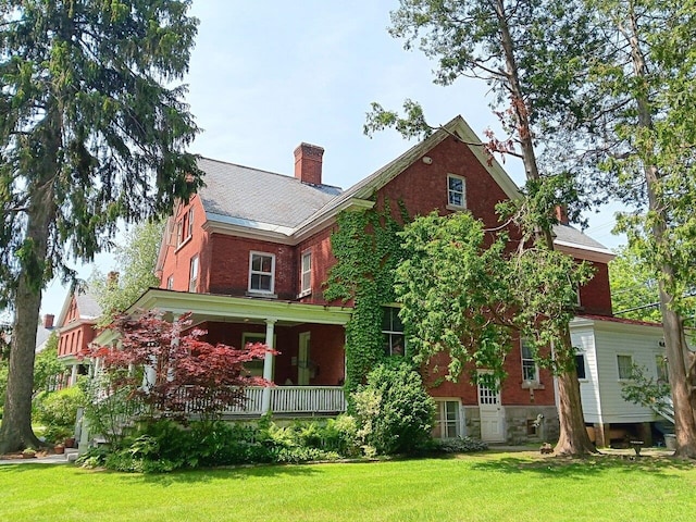 406 Dalton Dr Unit D, Colchester, VT 05446 - rear view of house featuring a yard, a chimney, covered porch, and brick siding