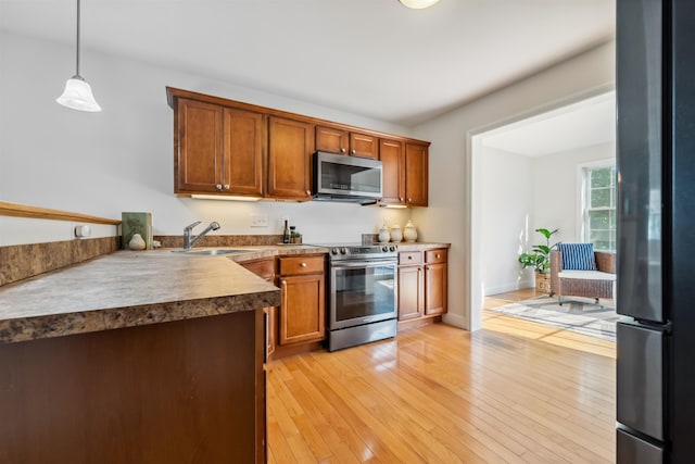 67 Leddy Dr, Epping, NH 03042 - kitchen with appliances with stainless steel finishes, a sink, decorative light fixtures, light wood-type flooring, and brown cabinetry