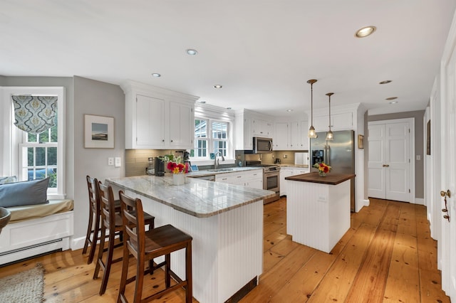 12 Ridgewood Ter, Exeter, NH 03833 - kitchen featuring stainless steel appliances, a sink, a peninsula, white cabinetry, and a baseboard heating unit