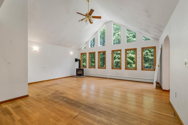 161 Frank C Gilman Hwy, Alton, NH 03809 - unfurnished living room featuring a wood stove, arched walkways, a ceiling fan, a baseboard radiator, and light wood finished floors