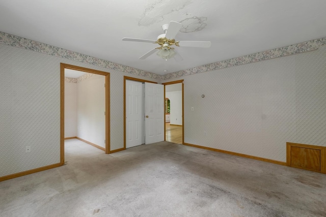 161 Frank C Gilman Hwy, Alton, NH 03809 - unfurnished bedroom with light carpet, baseboards, wallpapered walls, a ceiling fan, and two closets