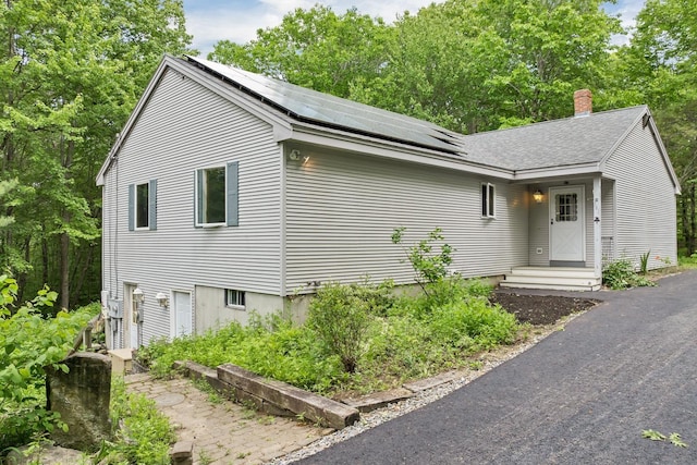 161 Frank C Gilman Hwy, Alton, NH 03809 - view of front of home featuring roof mounted solar panels, a chimney, and roof with shingles
