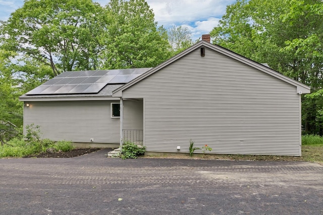161 Frank C Gilman Hwy, Alton, NH 03809 - view of home's exterior featuring roof mounted solar panels and a chimney