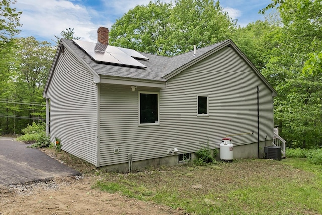 161 Frank C Gilman Hwy, Alton, NH 03809 - view of side of property with a shingled roof, roof mounted solar panels, central air condition unit, and a chimney