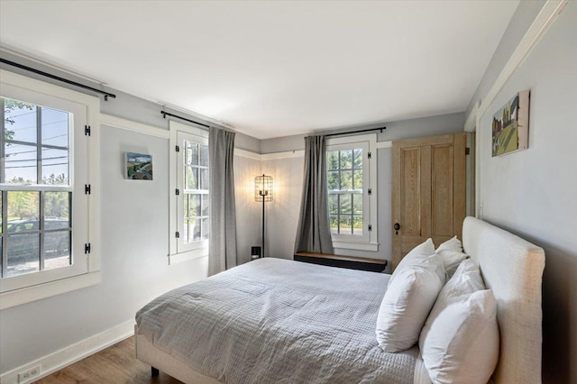 4780 Mountain Rd, Stowe, VT 05672 - bedroom featuring wood finished floors, baseboards, and multiple windows