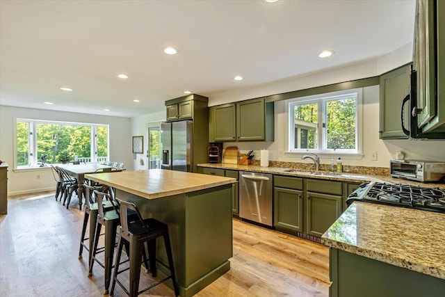 165 Golf Course Rd, Warren, VT 05674 - kitchen featuring green cabinetry, stainless steel appliances, a sink, a kitchen breakfast bar, and butcher block countertops