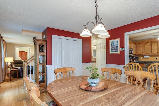 50 Kienia Rd, Hudson, NH 03051 - dining space with a textured ceiling, light wood-style flooring, a wainscoted wall, and stairs