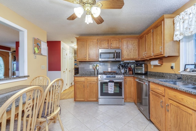 50 Kienia Rd, Hudson, NH 03051 - kitchen featuring stainless steel appliances, ceiling fan, a sink, light tile patterned floors, and brown cabinetry