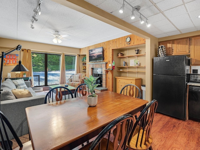 137 E Mountain Rd Unit 2A3, Killington, VT 05751 - dining space with rail lighting, ceiling fan, a brick fireplace, light wood-type flooring, and wood walls