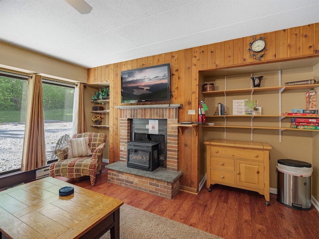 137 E Mountain Rd Unit 2A3, Killington, VT 05751 - living area featuring wood walls, wood finished floors, a wood stove, baseboards, and baseboard heating