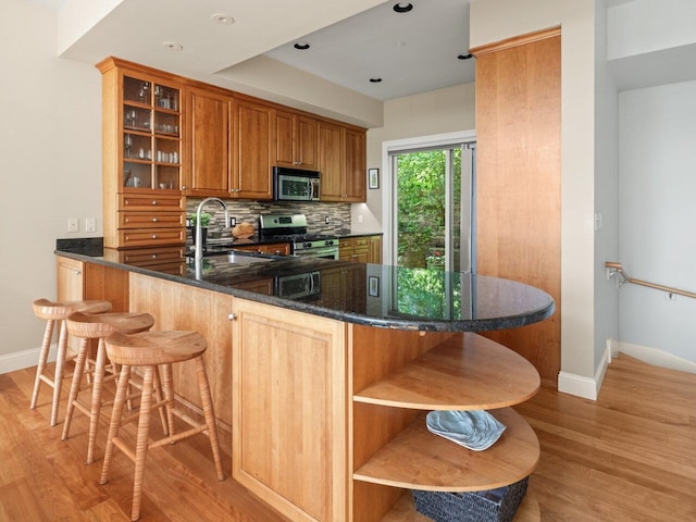 200 Lake St Unit 16, Burlington, VT 05401 - kitchen featuring stainless steel appliances, open shelves, a sink, light wood-type flooring, and baseboards