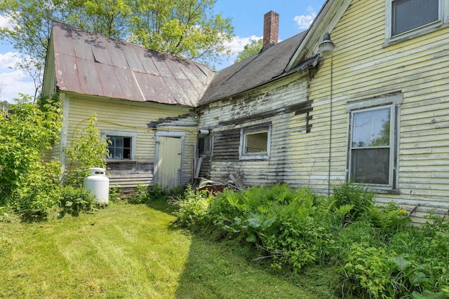 9 Laurel St, Whitefield, NH 03598 - back of property with a lawn, metal roof, and a chimney