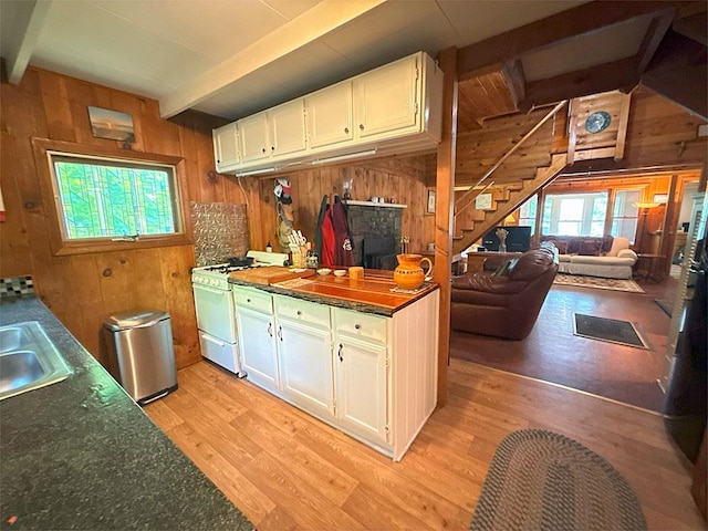 422/431 Little Rutland Rd, Castleton, VT 05735 - kitchen with white gas range oven, wooden walls, light wood-style flooring, white cabinets, and dark countertops