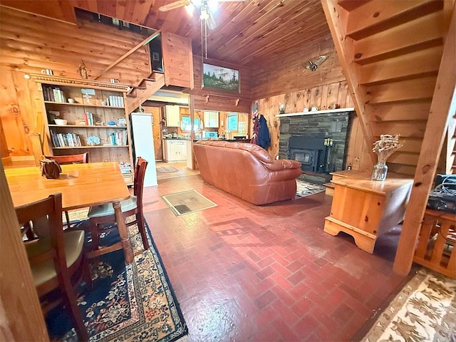 422/431 Little Rutland Rd, Castleton, VT 05735 - living room featuring brick floors, wooden walls, ceiling fan, wooden ceiling, and a stone fireplace