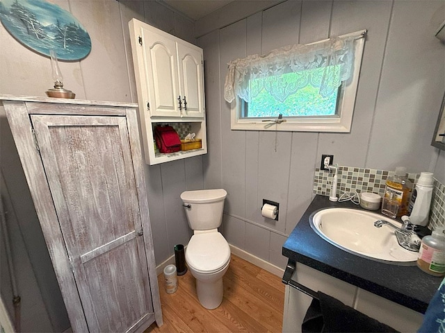 422/431 Little Rutland Rd, Castleton, VT 05735 - bathroom featuring wood finished floors, toilet, vanity, backsplash, and a decorative wall