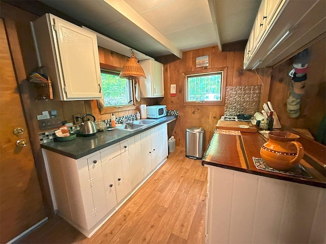 422/431 Little Rutland Rd, Castleton, VT 05735 - kitchen featuring white microwave, wooden walls, light wood-style floors, beamed ceiling, and a sink