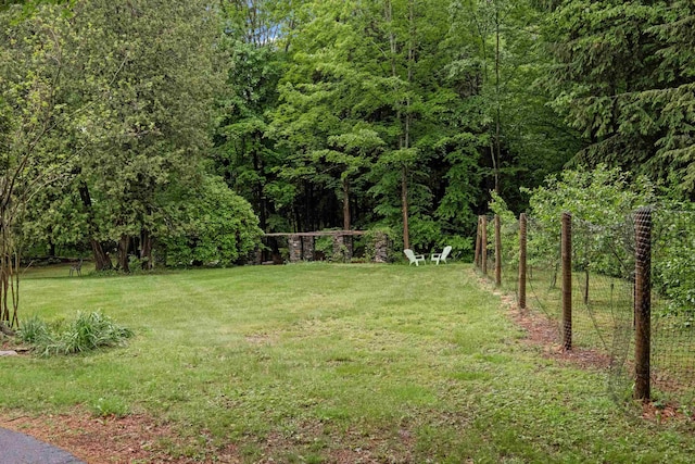 view of grassy yard with a view of trees