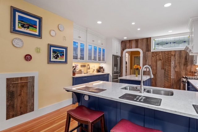 kitchen featuring blue cabinetry, stainless steel appliances, a sink, a kitchen breakfast bar, and white cabinets