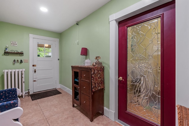 foyer with radiator heating unit, baseboards, and light tile patterned flooring