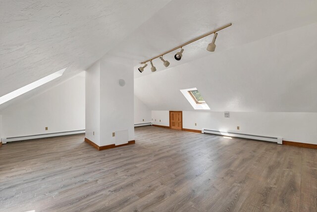 5 Lucerne Dr, Madison, NH 03849 - additional living space with a skylight, a baseboard radiator, vaulted ceiling, and wood finished floors