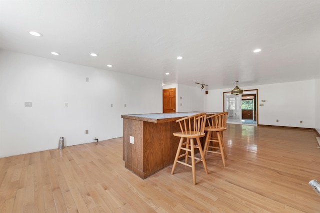 5 Lucerne Dr, Madison, NH 03849 - kitchen with light wood-style flooring, brown cabinets, recessed lighting, a breakfast bar, and a center island