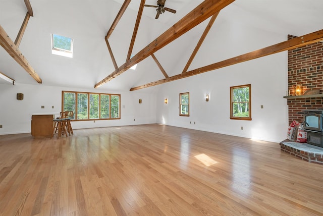 5 Lucerne Dr, Madison, NH 03849 - unfurnished living room featuring high vaulted ceiling, beamed ceiling, a wood stove, light wood-style flooring, and ceiling fan