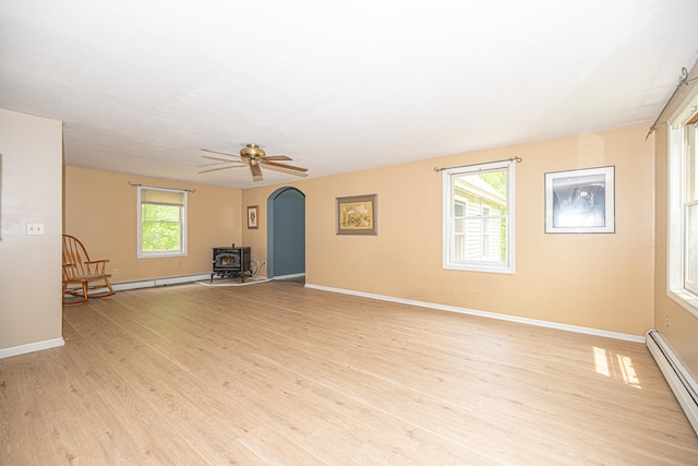 20 Locke Hill Ln, Barrington, NH 03825 - unfurnished living room with a baseboard heating unit, a wood stove, light wood-type flooring, baseboards, and ceiling fan