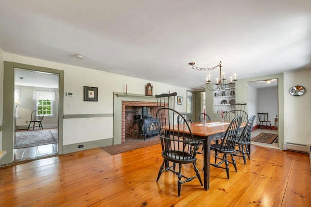 196 Deering Center Rd, Weare, NH 03281 - dining area featuring a wood stove, light wood finished floors, a baseboard heating unit, and a chandelier