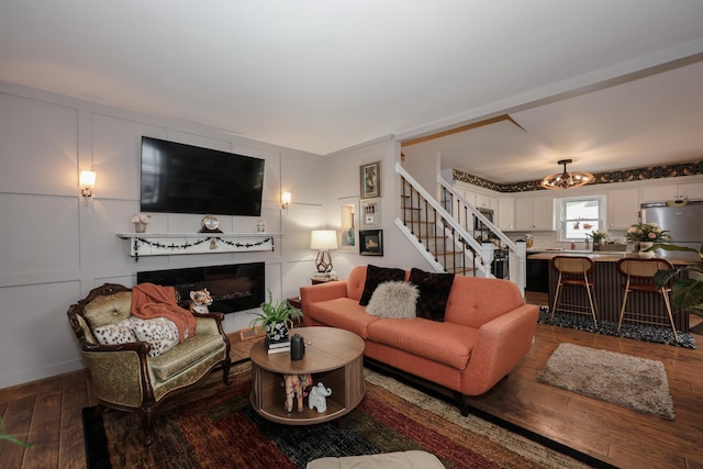 864 Cilley Rd, Manchester, NH 03103 - living room featuring stairs, hardwood / wood-style flooring, a glass covered fireplace, a decorative wall, and a chandelier