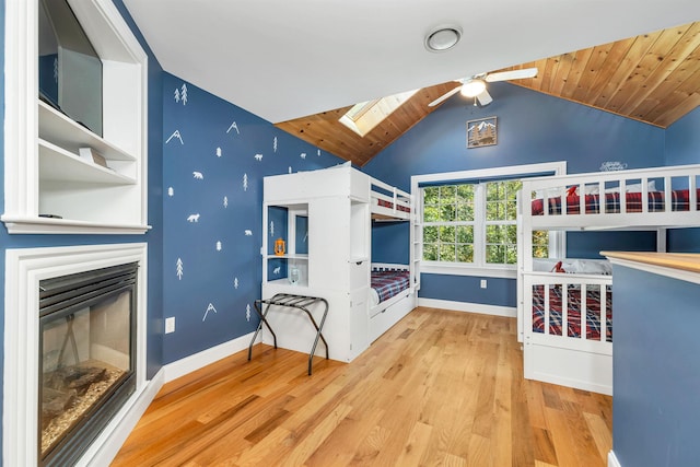 7 Acorn Dr, Alton, NH 03810 - unfurnished bedroom featuring wood finished floors, lofted ceiling, a skylight, baseboards, and a glass covered fireplace