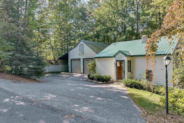 7 Acorn Dr, Alton, NH 03810 - view of front of property featuring a chimney, metal roof, a standing seam roof, and asphalt driveway