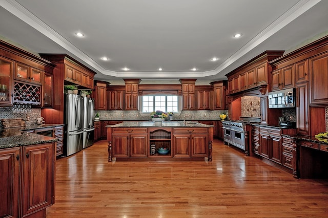 33 Winterberry Ln, Plymouth, NH 03264 - kitchen with stainless steel appliances, a center island with sink, light wood finished floors, crown molding, and decorative backsplash