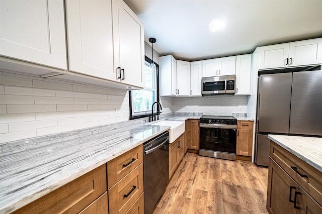 110 Currier Rd, Candia, NH 03034 - kitchen with stainless steel appliances, a sink, light stone countertops, and light wood-style floors