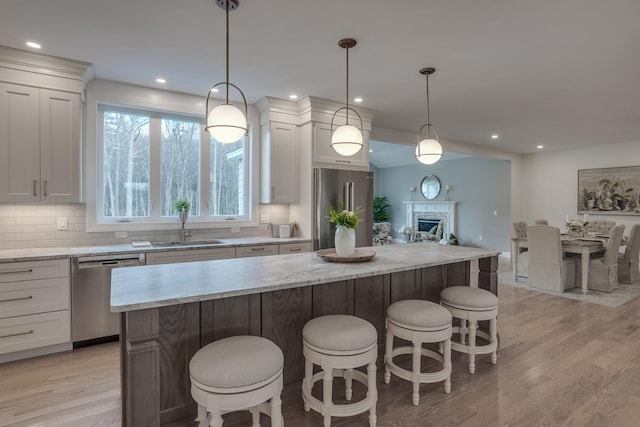 338 Pine Hill Rd, Hollis, NH 03049 - kitchen featuring stainless steel appliances, a sink, light wood-style floors, a center island, and a kitchen bar