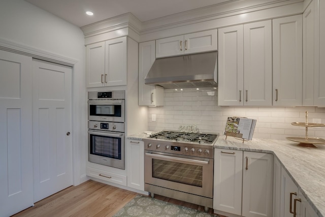 338 Pine Hill Rd, Hollis, NH 03049 - kitchen with under cabinet range hood, stainless steel appliances, light wood-type flooring, tasteful backsplash, and white cabinets