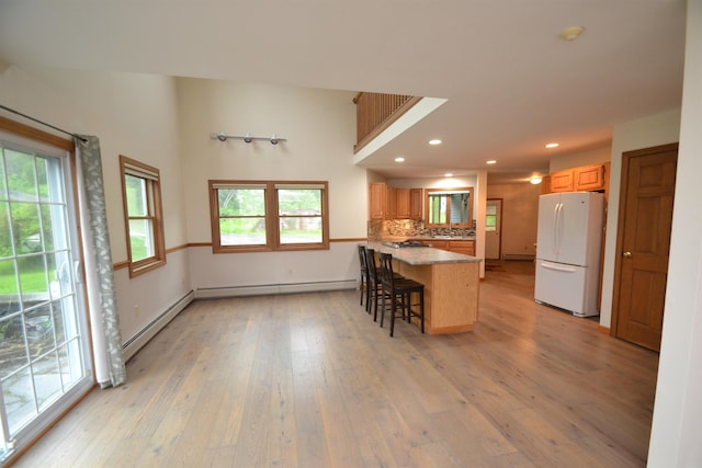 296 Atwood Rd, Duxbury, VT 05676 - kitchen featuring freestanding refrigerator, light wood finished floors, a kitchen breakfast bar, recessed lighting, and a peninsula
