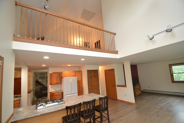 296 Atwood Rd, Duxbury, VT 05676 - kitchen with white appliances, baseboard heating, a high ceiling, light wood finished floors, and a breakfast bar area