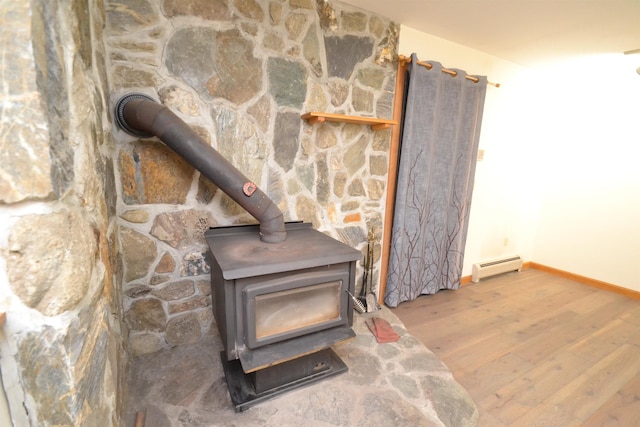 296 Atwood Rd, Duxbury, VT 05676 - detailed view of baseboard heating, a wood stove, wood finished floors, and baseboards