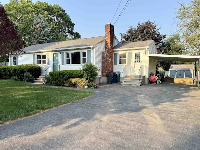 22 Sanborn Rd, Hampton, NH 03842 - view of front facade with a chimney, driveway, a carport, a front yard, and a shingled roof