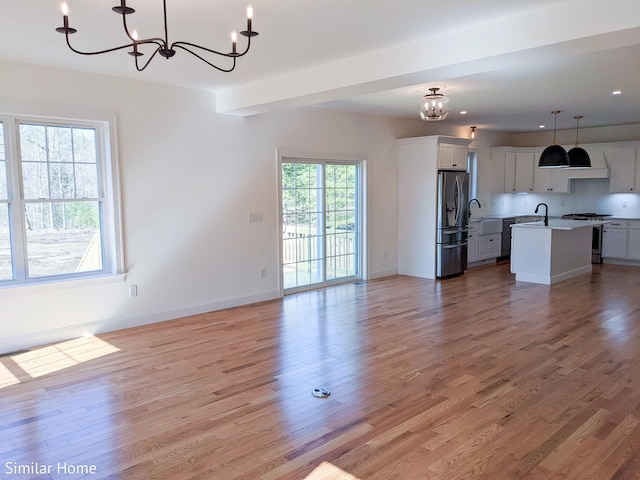 LOT7-3 Sanborn Mdw Unit 7-3, Fremont, NH 03044 - unfurnished living room featuring a chandelier, a sink, light wood-type flooring, and baseboards