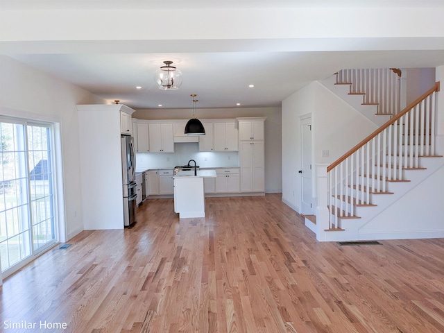 LOT7-3 Sanborn Mdw Unit 7-3, Fremont, NH 03044 - kitchen featuring open floor plan, a center island with sink, light wood finished floors, freestanding refrigerator, and white cabinets