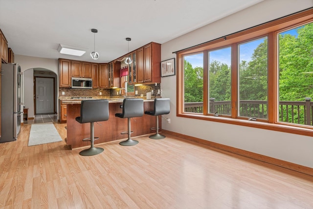 290 Cornish Tpke, Newport, NH 03773 - kitchen with stainless steel appliances, arched walkways, light wood-style flooring, decorative backsplash, and a peninsula