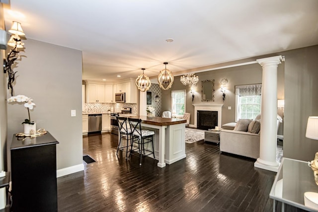 4 Crossman Cir, Newton, NH 03858 - kitchen with stainless steel appliances, open floor plan, a breakfast bar, backsplash, and a fireplace