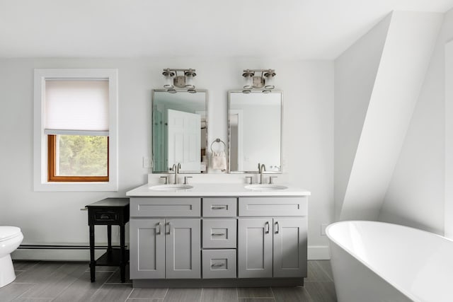 6 Paquette Ln, Sunapee, NH 03782 - bathroom featuring a baseboard radiator, a freestanding bath, double vanity, toilet, and baseboards