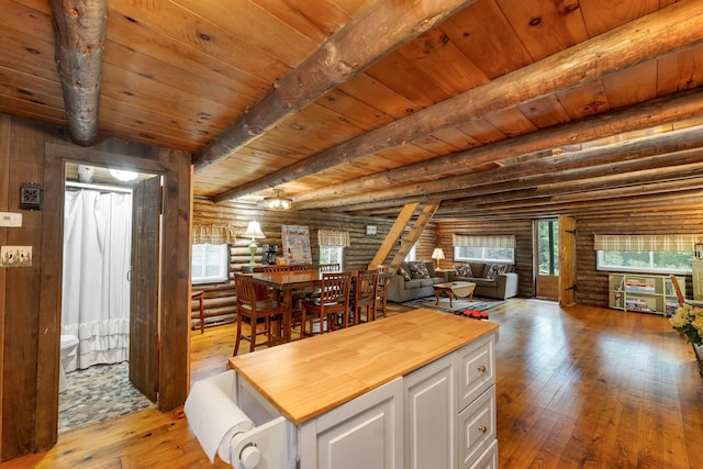 230 Pine Hill Rd, Ossipee, NH 03864 - kitchen with log walls, wooden counters, light wood finished floors, white cabinets, and wood ceiling with exposed beams