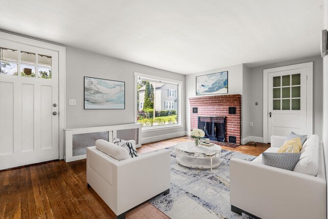 33 Hayes Ave, Manchester, NH 03103 - living area with radiator, hardwood / wood-style flooring, a brick fireplace, and baseboards