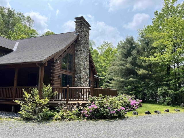 27 Stearns Ave, Wilmington, VT 05363 - view of home's exterior featuring log siding, a chimney, a shingled roof, and a deck