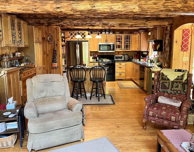 27 Stearns Ave, Wilmington, VT 05363 - kitchen featuring black appliances, light wood finished floors, dark countertops, glass insert cabinets, and a kitchen breakfast bar