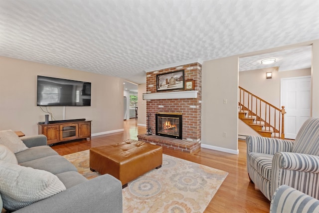 6 Bona Vista Dr, Bow, NH 03304 - living area with a textured ceiling, light wood-style floors, stairs, a fireplace, and baseboards
