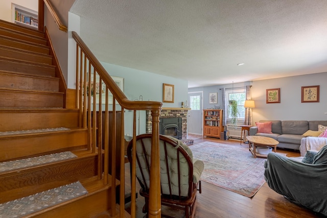 15 Allens Ave, Lee, NH 03861 - living room featuring wood finished floors, stairway, a textured ceiling, radiator, and a fireplace